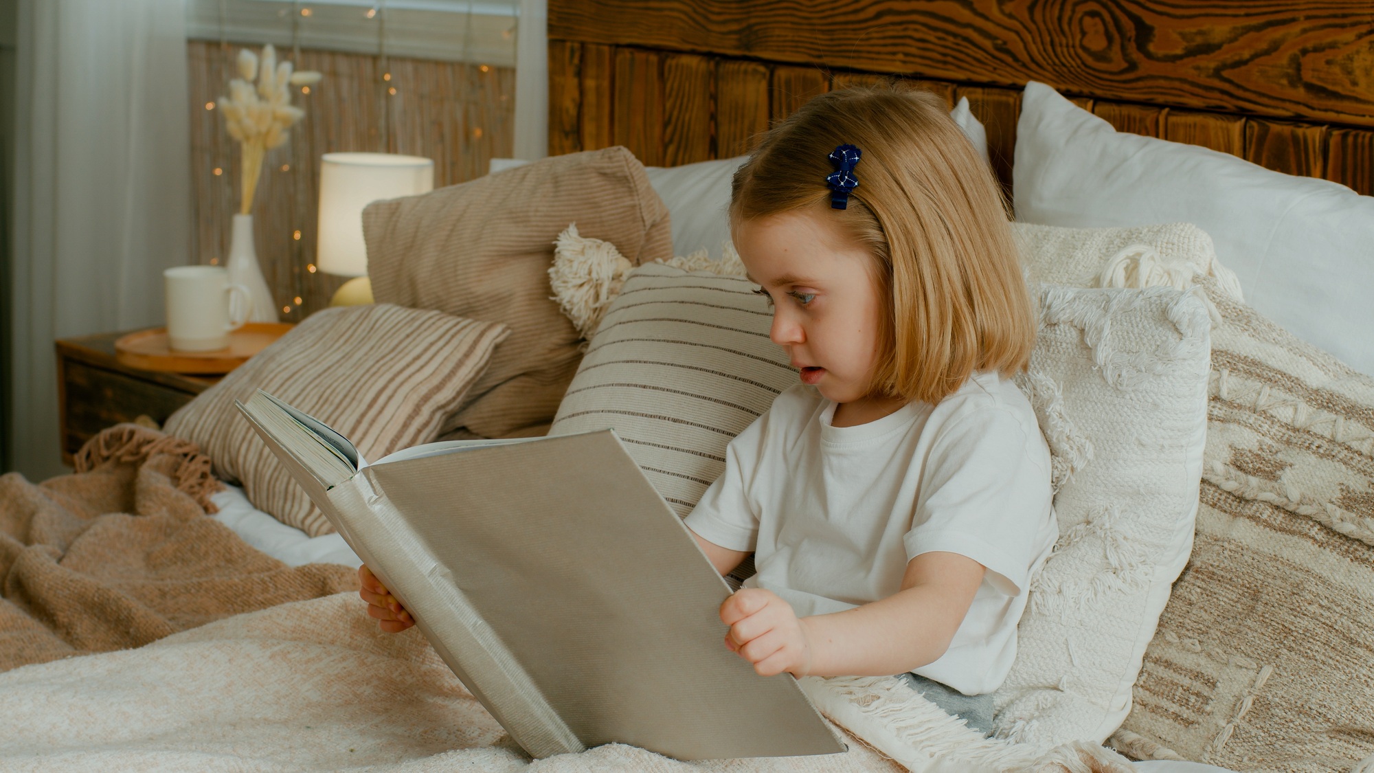 Cute little 5s Caucasian alone child girl daughter looking in book kid preschool baby sitting in bed