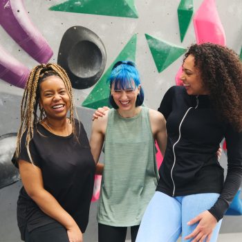 Portrait Of Group Of Female Multi-Cultural Friends By Climbing Wall At Indoor Activity Centre